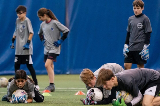 Goalkeeper practicing agility and reflex drills with cones during a small group training session in Quebec.
